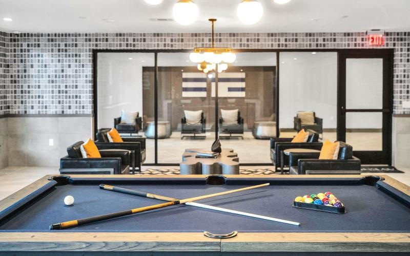 a room with a pool table and chairs